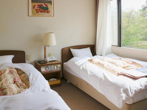 a hotel room with two beds and a window at Tabist Niitsuru Onsen Nda in Aizumisato