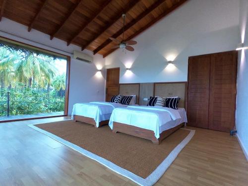 a bedroom with two beds and a large window at Vandalous Bay in Pasikuda