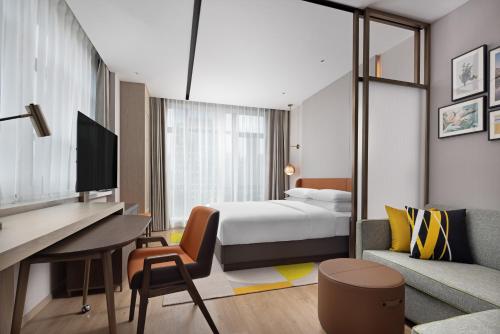 貴陽市にあるHome2 Suites by Hilton Guiyang Guanshanhuのベッドとデスクが備わるホテルルームです。