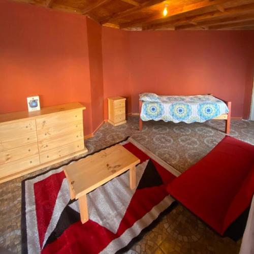 a bedroom with a bed and a dresser and a table at Cabaña Altos de Chanchoqui in Paihuano