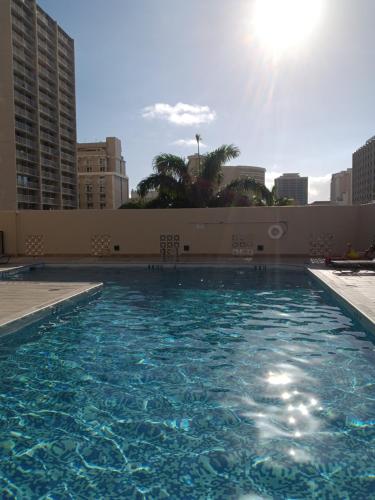 een zwembad met blauw water in een stad bij Royal Kuhio 1710 - Spacious Studio with Stunning Ocean City Views in the Heart of Waikiki! in Honolulu