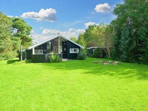 a black house in a yard with a green lawn at 6 person holiday home in Græsted-By Traum in Græsted