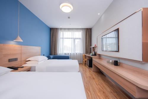 a hotel room with two beds and a flat screen tv at Future Shangju Hotel in Shanghai