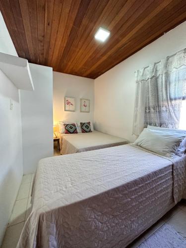 a bedroom with two beds and a wooden ceiling at Pousada Morena in Morro de São Paulo