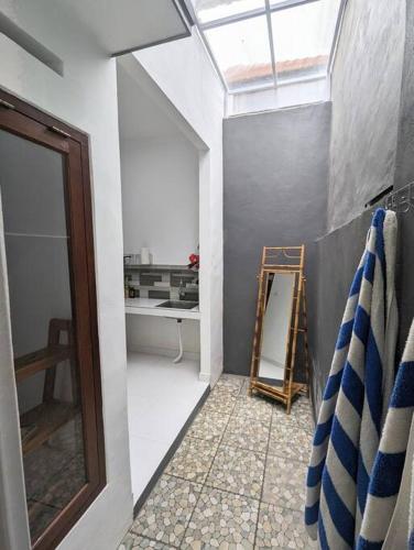 een badkamer met een raam, een ladder en een spiegel bij Mini tropical home with office in Krambitan