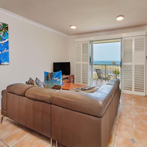 un gran sofá marrón en la sala de estar con vistas al océano en Cabarita Beachfront Apartments by Kingscliff Accommodation, en Cabarita Beach