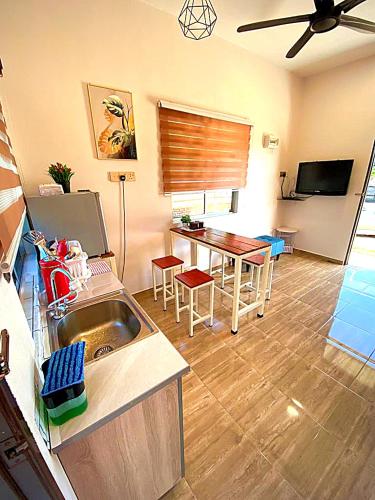 a kitchen and living room with a sink and a table at Palas Tiny Homestay in Changlun