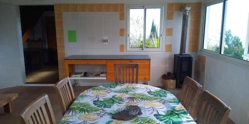 a dining room with a table and chairs and two windows at Le Tranquillou in La Plaine des Cafres