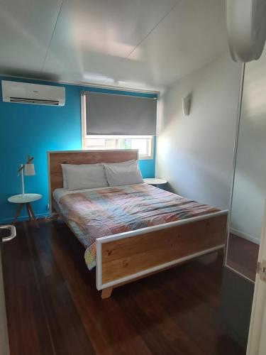 uma cama num pequeno quarto com uma parede azul em Allure Stradbroke Resort em Point Lookout