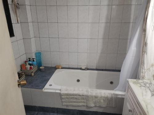 uma banheira branca numa casa de banho com uma parede de azulejos brancos em Casa del Limón em Valparaíso