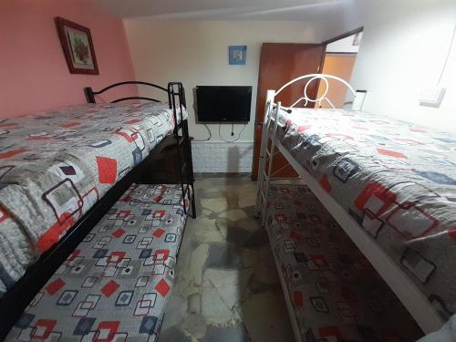 2 camas individuais num quarto com uma televisão em cabaña alma dorada em Huerta Grande