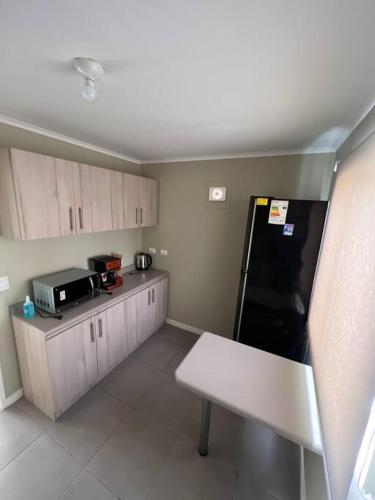 a kitchen with a white bench and a black refrigerator at Casa Nueva 3 dormitorios 2B in Puerto Montt