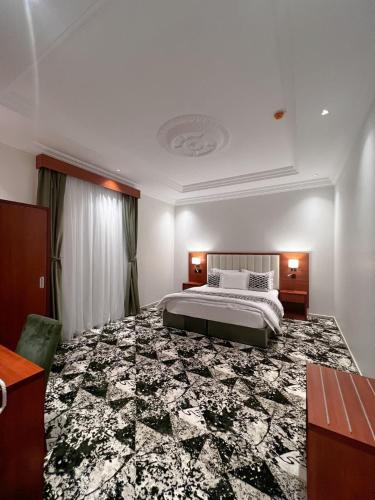 a bedroom with a large bed with a black and white rug at رواح للشقق المخدومة السداد in Taif