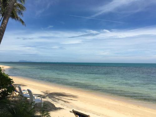 a beach with two white chairs and the ocean at Bangpo Village in Ban Bang Po