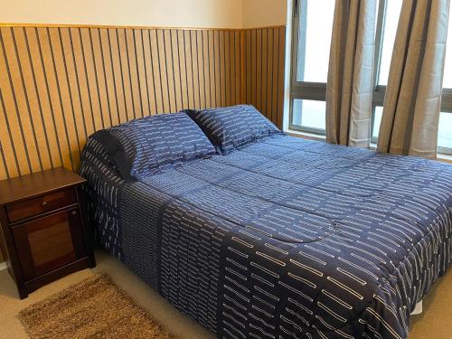 a bedroom with a blue bed and a wooden wall at Departamento Frente al Mar, Playa Bellavista, Tome in Tomé