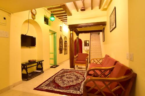 einen Flur mit einem Wohnzimmer mit Stühlen und einem TV in der Unterkunft Villa Dumont in Puducherry