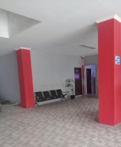 una stanza con colonne e sedie rosse in un edificio di HER MANDIRI GUEST HOUSE a Balikpapan