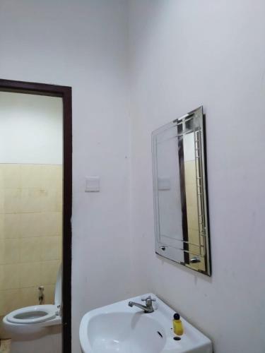 uma casa de banho com um lavatório, um espelho e um WC. em HER MANDIRI GUEST HOUSE em Balikpapan