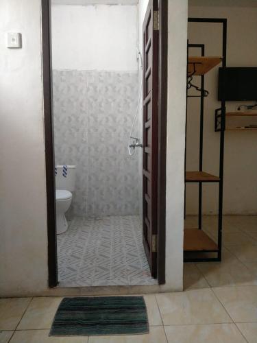 ein Bad mit einer Dusche und einem WC in einem Zimmer in der Unterkunft HER MANDIRI GUEST HOUSE in Balikpapan