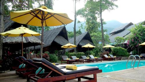 a pool with chairs and umbrellas and a table with a table at Banpu Koh Chang Resort in Ko Chang