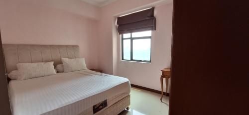 ein kleines Schlafzimmer mit einem Bett und einem Fenster in der Unterkunft Sudirman Tower Condominium in Jakarta
