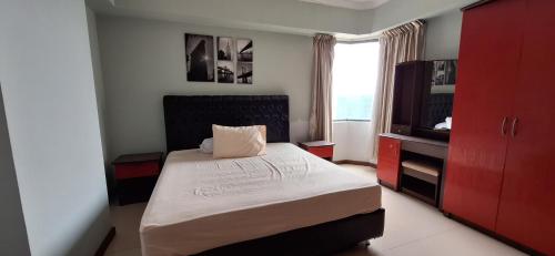 ein kleines Schlafzimmer mit einem Bett und einem TV in der Unterkunft Sudirman Tower Condominium in Jakarta