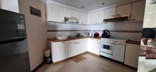 eine kleine Küche mit weißen Schränken und einem Herd in der Unterkunft Sudirman Tower Condominium in Jakarta