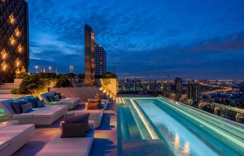 a pool on the roof of a building at night at INNSiDE by Meliá Bangkok Sukhumvit in Bangkok