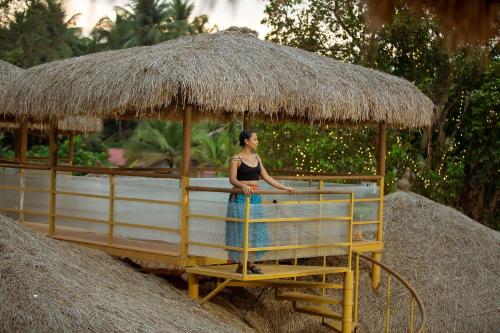 a woman standing on a ride in a straw hut at One At Goa in Canacona