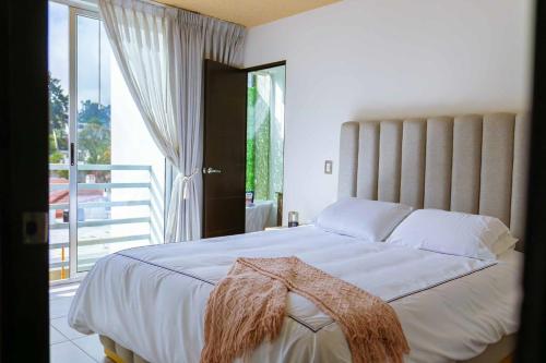 ein Schlafzimmer mit einem großen Bett und einem großen Fenster in der Unterkunft Apartamento a unas cuadras de Condado Concepción Carretera a El Salvador in Guatemala