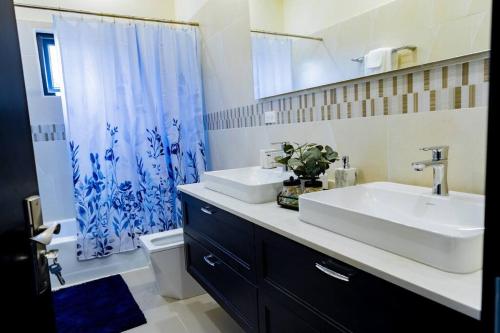 a bathroom with a sink and a blue shower curtain at Pyramid Point Manor in Ocho Rios