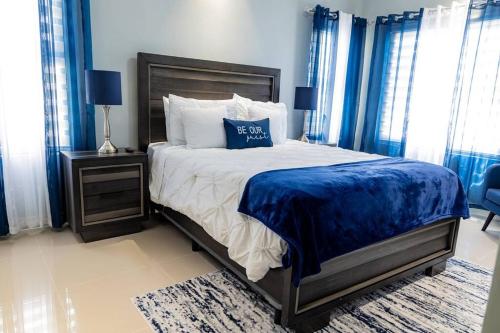 una camera da letto con un letto grande con lenzuola e cuscini blu di Pyramid Point Manor a Ocho Rios