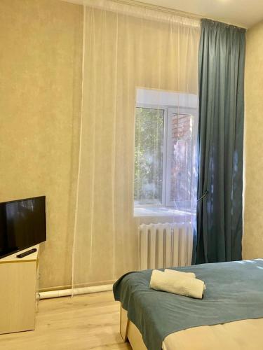 Schlafzimmer mit einem Bett, einem TV und einem Fenster in der Unterkunft Однокомнатный номер эконом класса 