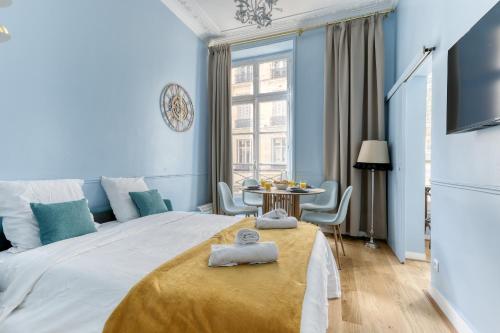 - une chambre bleue avec un grand lit et une table dans l'établissement The Typical Parisian Flat - Louvre Royal - Paris 1, à Paris