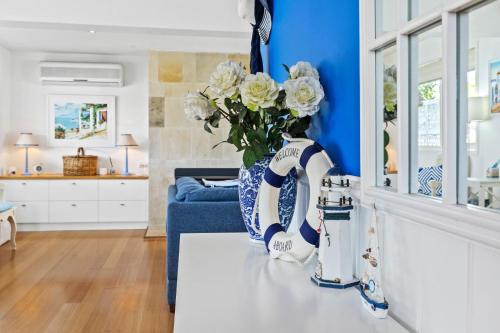 uma cozinha azul e branca com um vaso de flores no balcão em SANTORINI BEACH HOUSE SAFETY BEACH em Safety Beach