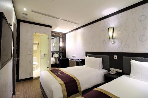 a hotel room with two beds and a bathroom at J-HOTEL in Kaohsiung