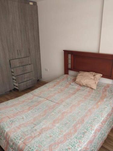 a bedroom with a bed with a pillow and a dresser at Departamento moderno y amoblado in Quito