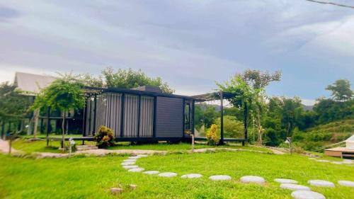a house in the middle of a grassy yard with a path at Ora Hill Retreat in Cao Phong