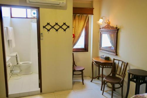 a bathroom with a toilet and a table and chairs at Fulay Hotel in Hua Hin