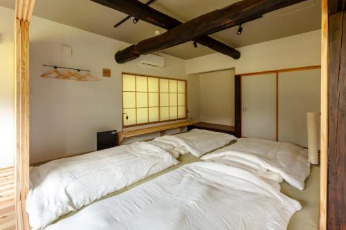 a large bed in a room with white sheets at Okuaga nanamean Rakura in Aga