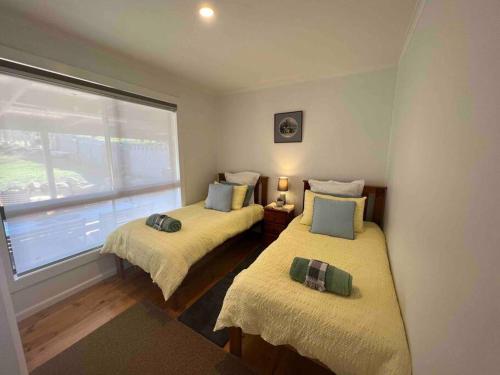 two beds in a room with a window at Chillin at Adaminaby FSC home in Adaminaby in Adaminaby