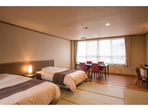 那須塩原市にある美肌の湯と寛ぎの宿 光雲荘のベッド2台、テーブルと椅子が備わるホテルルームです。