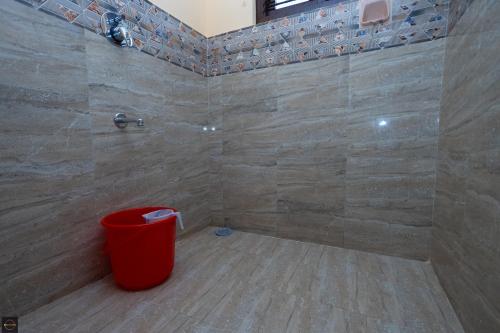 a bathroom with a shower with a red trash can at Reunion Regal Villa in Udupi