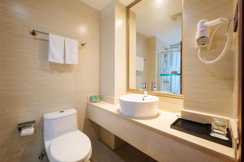 een badkamer met een toilet, een wastafel en een spiegel bij Xiamen Xiangzun Hotel - Huijing Plaza Branch in Xiamen