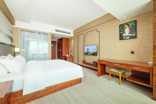 een slaapkamer met een groot bed en een bureau bij Xiamen Xiangzun Hotel - Huijing Plaza Branch in Xiamen