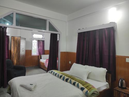 a hotel room with a bed and a chair at Hotel Tawang Regency in Tawang
