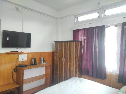 a bedroom with a bed and a tv on the wall at Hotel Tawang Regency in Tawang