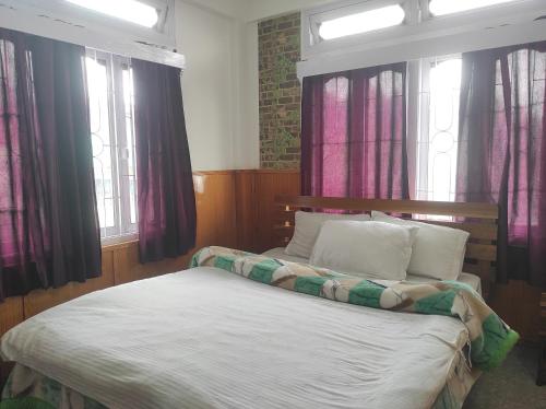 a bed sitting in a room with windows at Hotel Tawang Regency in Tawang
