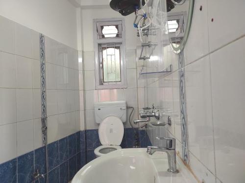 a bathroom with a sink and a toilet and a window at Hotel Tawang Regency in Tawang