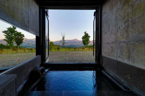 a view from a window of a bath tub with water at Ryokan Konomama in Minami Aso
